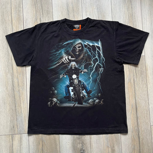 Rock Eagle 2010s Skull Biker Tee is a black T-shirt featuring a large front graphic of a skull-faced biker riding a motorcycle while being chased by a skeletal Grim Reaper holding a scythe. The artwork includes lightning strikes, skulls, and detailed airbrush-style effects throughout the scene. The back features a graphic of a winged engine with a skull at the center. Finished with a Rock Eagle neck tag.
