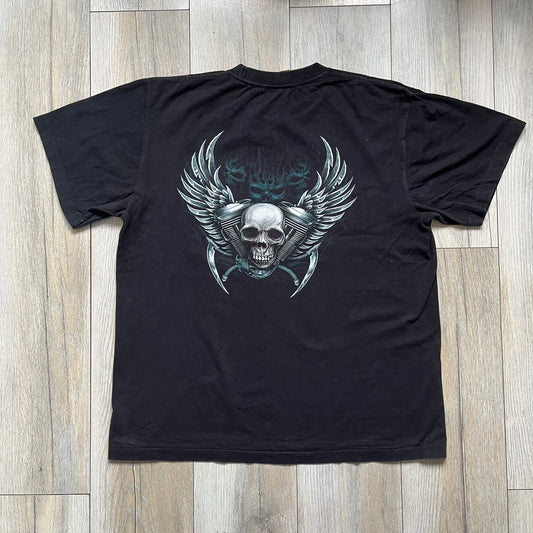 Rock Eagle 2010s Skull Biker Tee is a black T-shirt featuring a large front graphic of a skull-faced biker riding a motorcycle while being chased by a skeletal Grim Reaper holding a scythe. The artwork includes lightning strikes, skulls, and detailed airbrush-style effects throughout the scene. The back features a graphic of a winged engine with a skull at the center. Finished with a Rock Eagle neck tag.
