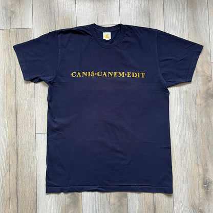 Rockstar Games 'Canis Canem Edit (Bully)' Navy Tee is a dark navy T-shirt made in the USA featuring a yellow "Canis Canem Edit" text on the chest, referencing the original Bully game title. The back displays a large yellow Bullworth Academy logo, while a small yellow Rockstar logo is printed on the sleeve. The shirt includes an official Rockstar Games neck tag.