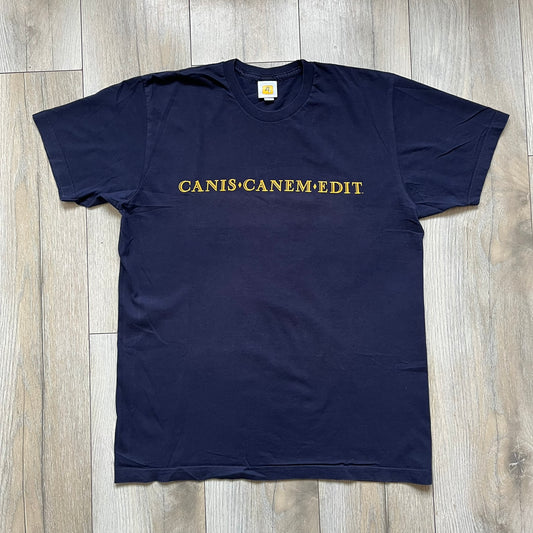 Rockstar Games 'Canis Canem Edit (Bully)' Navy Tee is a dark navy T-shirt made in the USA featuring a yellow "Canis Canem Edit" text on the chest, referencing the original Bully game title. The back displays a large yellow Bullworth Academy logo, while a small yellow Rockstar logo is printed on the sleeve. The shirt includes an official Rockstar Games neck tag.