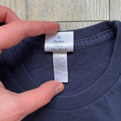 Rockstar Games 'Canis Canem Edit (Bully)' Navy Tee is a dark navy T-shirt made in the USA featuring a yellow "Canis Canem Edit" text on the chest, referencing the original Bully game title. The back displays a large yellow Bullworth Academy logo, while a small yellow Rockstar logo is printed on the sleeve. The shirt includes an official Rockstar Games neck tag.