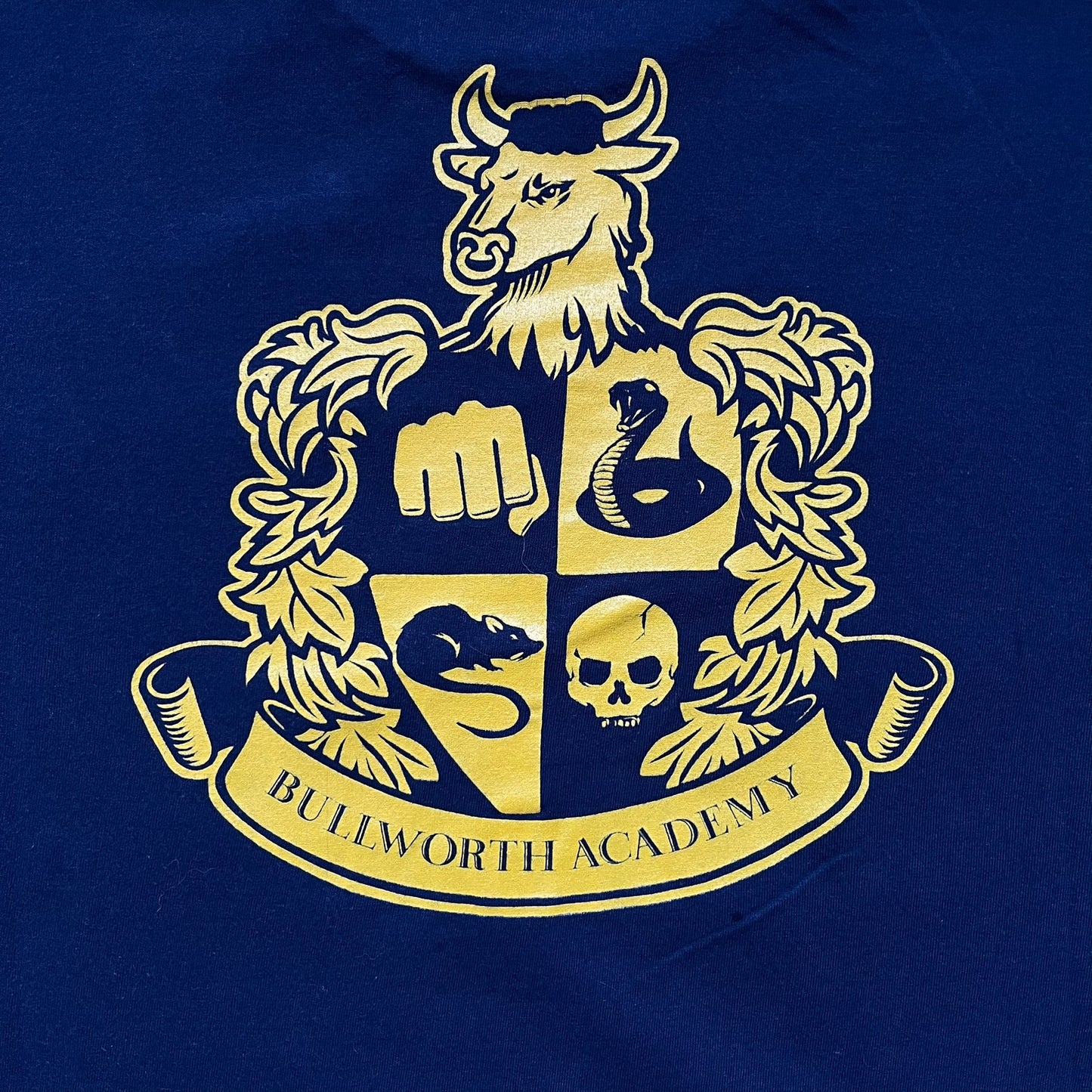 Rockstar Games 'Canis Canem Edit (Bully)' Navy Tee is a dark navy T-shirt made in the USA featuring a yellow "Canis Canem Edit" text on the chest, referencing the original Bully game title. The back displays a large yellow Bullworth Academy logo, while a small yellow Rockstar logo is printed on the sleeve. The shirt includes an official Rockstar Games neck tag.