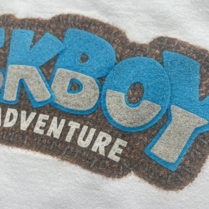 Sackboy: A Big Adventure 2020 White Promo Tee is a white cotton T-shirt featuring official Sony licensing and a “not for sale” internal tag. The front includes a small printed faux chest pocket design with Sackboy waving from inside it. The upper back displays a large “Sackboy: A Big Adventure” game logo print.