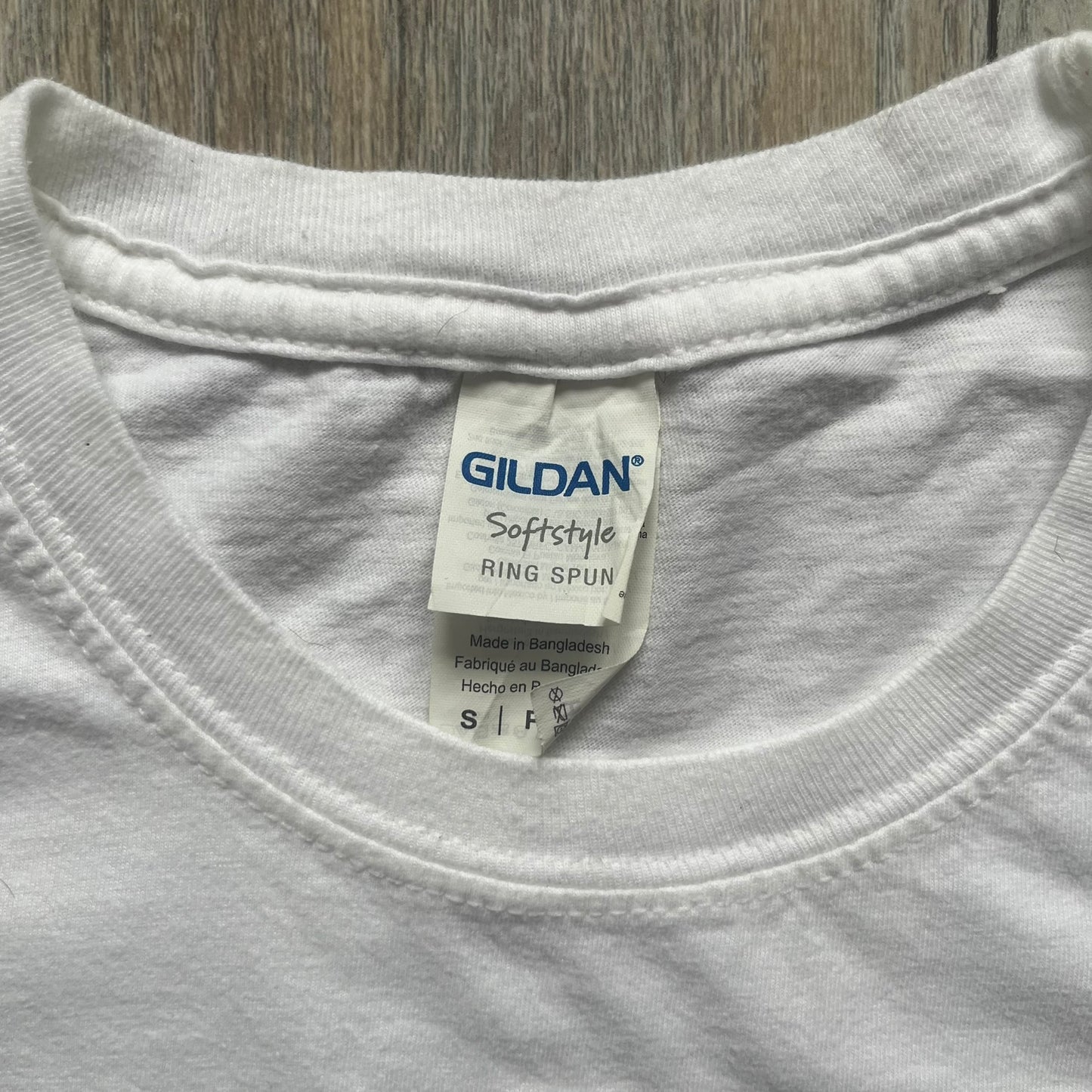 Sackboy: A Big Adventure 2020 White Promo Tee is a white cotton T-shirt featuring official Sony licensing and a “not for sale” internal tag. The front includes a small printed faux chest pocket design with Sackboy waving from inside it. The upper back displays a large “Sackboy: A Big Adventure” game logo print.