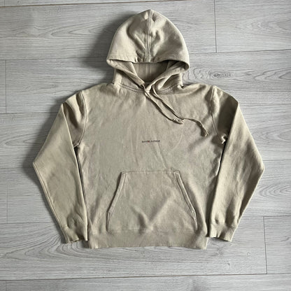 Crafted in France from 100% cotton, this Saint Laurent Beige Hoodie features a minimalist aesthetic with the brand’s signature small Saint Laurent chest logo and red square detail. Designed with a classic front pocket and clean drawstrings without metal tips, it delivers understated Parisian luxury in a neutral tone.