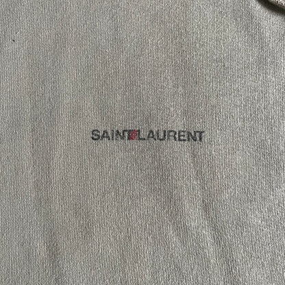 Crafted in France from 100% cotton, this Saint Laurent Beige Hoodie features a minimalist aesthetic with the brand’s signature small Saint Laurent chest logo and red square detail. Designed with a classic front pocket and clean drawstrings without metal tips, it delivers understated Parisian luxury in a neutral tone.