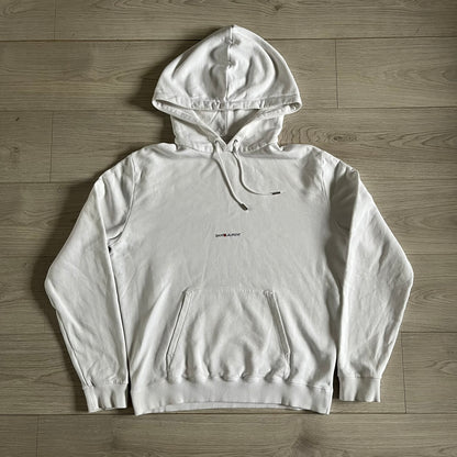 Saint Laurent Small Logo White Hoodie made in France from 100% cotton. Features a minimalist chest logo with “Saint” and “Laurent” separated by a small red square, silver-tipped drawstrings engraved with branding, and a classic front pocket. Designed with the brand’s signature minimalist aesthetic.