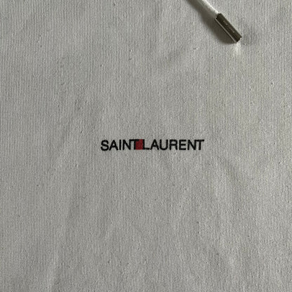 Saint Laurent Small Logo White Hoodie made in France from 100% cotton. Features a minimalist chest logo with “Saint” and “Laurent” separated by a small red square, silver-tipped drawstrings engraved with branding, and a classic front pocket. Designed with the brand’s signature minimalist aesthetic.