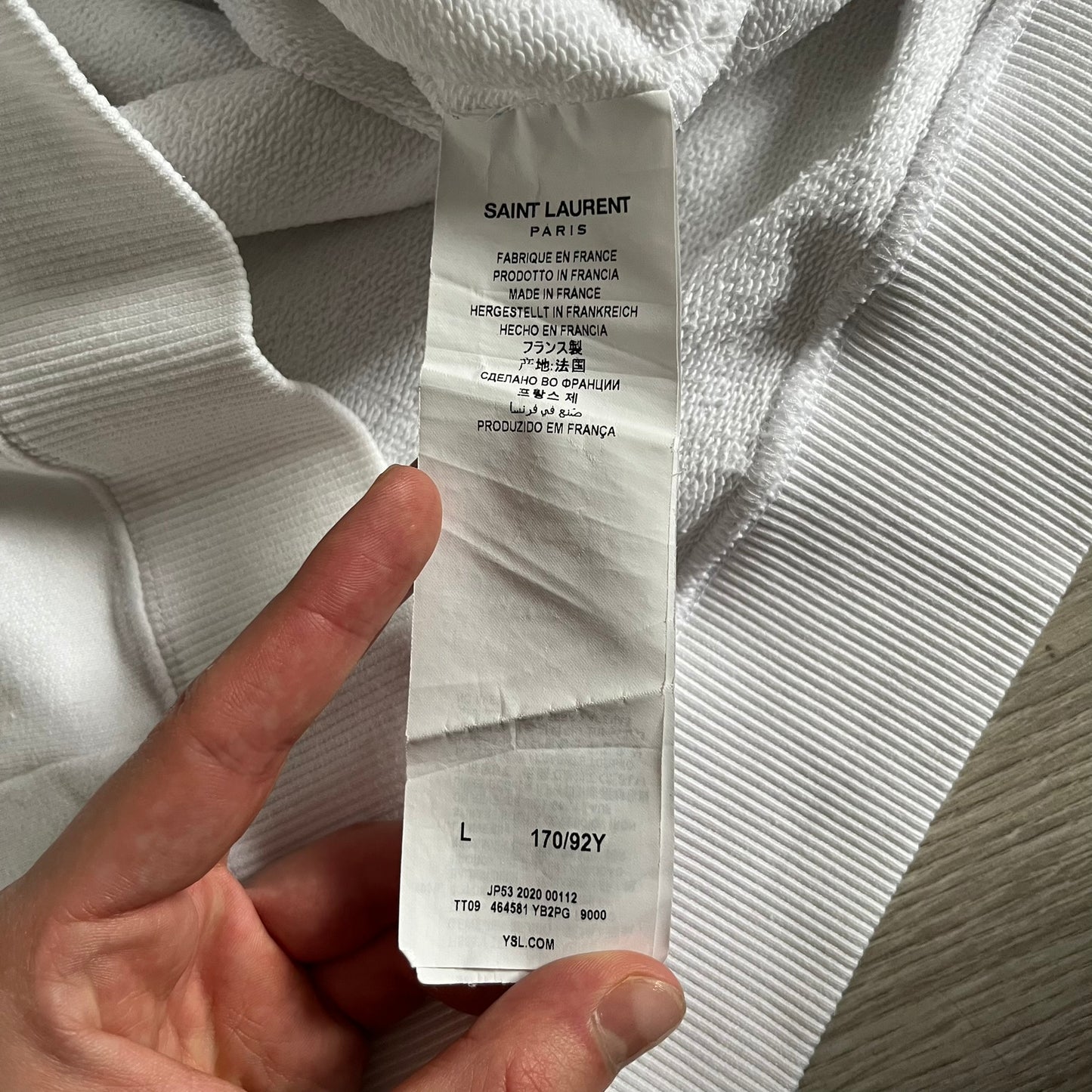 Saint Laurent Small Logo White Hoodie made in France from 100% cotton. Features a minimalist chest logo with “Saint” and “Laurent” separated by a small red square, silver-tipped drawstrings engraved with branding, and a classic front pocket. Designed with the brand’s signature minimalist aesthetic.