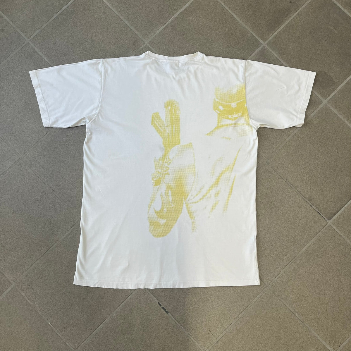 Saints Row 2 x PLNY Textylia 2008 White Promo Tee is a rare Poland-exclusive promotional shirt released for Saints Row 2 in collaboration with Polish brand PLNY Textylia, limited to a numbered run (this piece numbered #00059). The front features a black and white Saints Row 2 logo over yellow tribal graphics with a smaller PLNY Textylia logo below, plus a patch displaying both brand logos, while the back carries a large yellow dot/square-style graphic of the game's cover character.