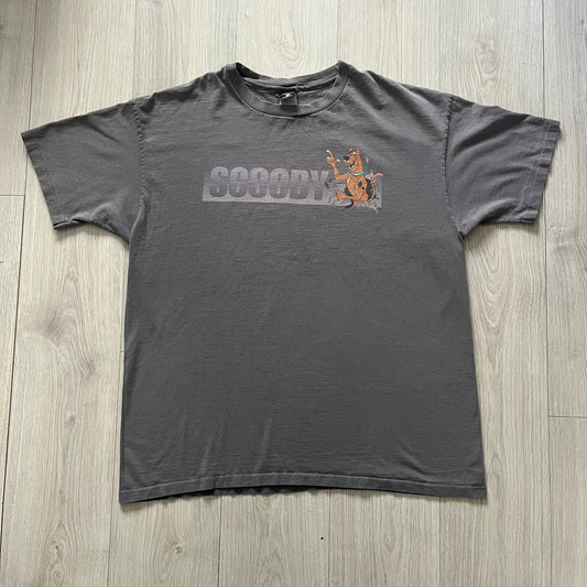 Gray Scooby-Doo tee from 1998, officially licensed by Warner Bros. Studio Store. Graphic shows Scooby emerging through the shirt as if he tore it, paired with classic text. Single-stitch USA-made construction adds authentic vintage charm.