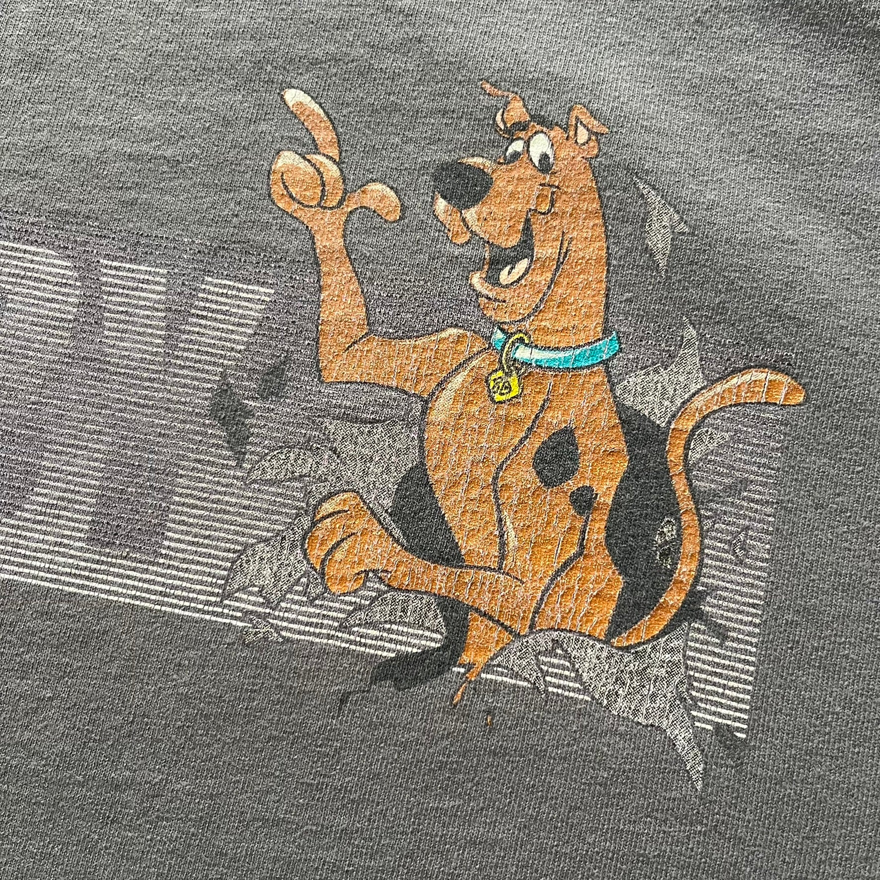 Gray Scooby-Doo tee from 1998, officially licensed by Warner Bros. Studio Store. Graphic shows Scooby emerging through the shirt as if he tore it, paired with classic text. Single-stitch USA-made construction adds authentic vintage charm.