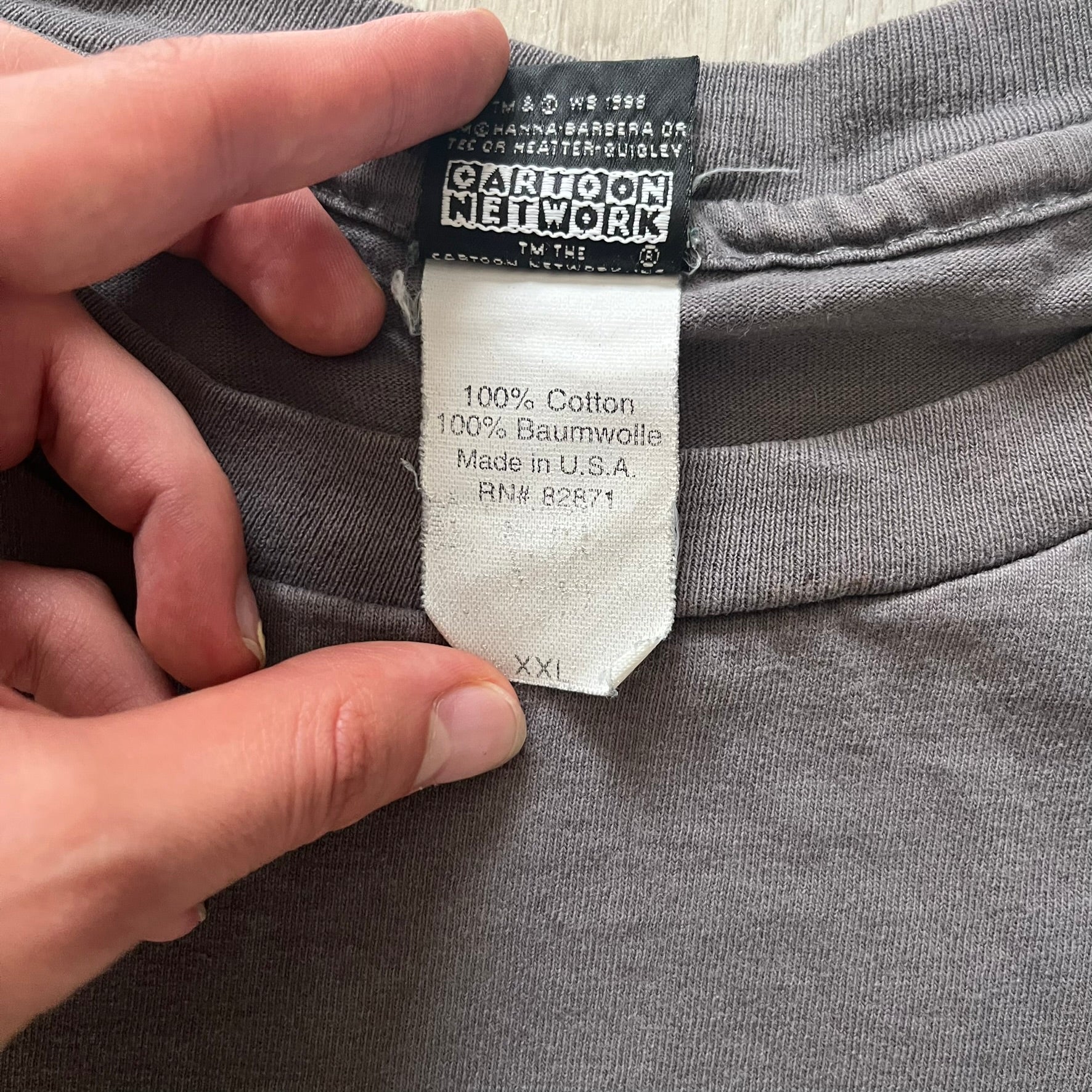 Gray Scooby-Doo tee from 1998, officially licensed by Warner Bros. Studio Store. Graphic shows Scooby emerging through the shirt as if he tore it, paired with classic text. Single-stitch USA-made construction adds authentic vintage charm.