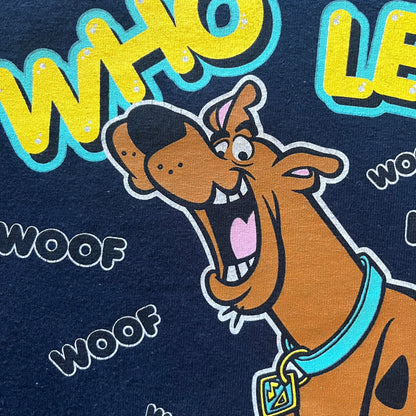 Vintage 2000 Scooby-Doo “Who Let The Dog Out” tee in Navy. Features a big colorful graphic of Scooby running, framed by “Who Let The Dog Out” and playful “Woof” prints. Licensed by Hanna-Barbera with the original green Scooby-Doo tag.