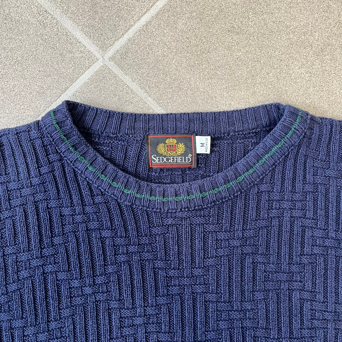 Sedgefield 1990's Basketweave Navy Sweater is a heavyweight navy sweater made in the USA, featuring a thin green line detail on the collar.
