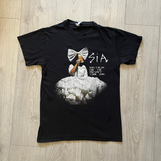  Sia 2016 Nostalgic For The Present tour tee in black, printed on a durable Delta Pro Weight blank. The front features a Sia graphic, while the back lists all U.S. tour cities where she performed. Made as official merchandise for the 2016 tour, this tee combines quality construction with collectible tour details.