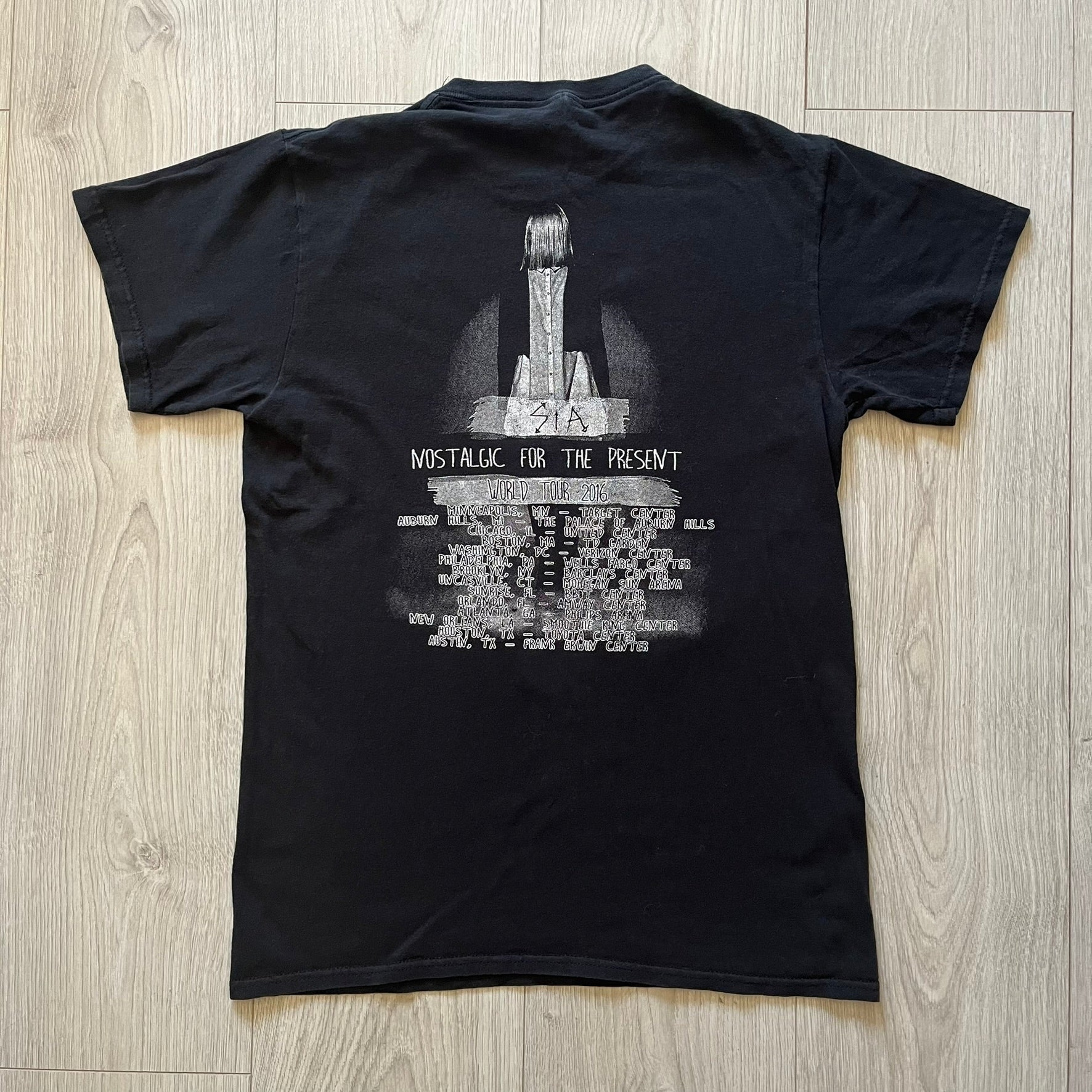  Sia 2016 Nostalgic For The Present tour tee in black, printed on a durable Delta Pro Weight blank. The front features a Sia graphic, while the back lists all U.S. tour cities where she performed. Made as official merchandise for the 2016 tour, this tee combines quality construction with collectible tour details.