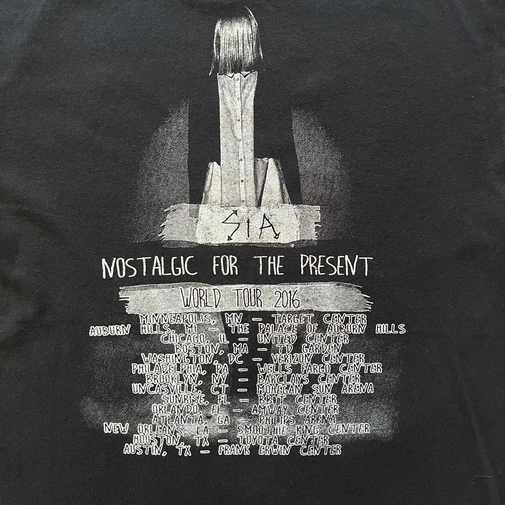  Sia 2016 Nostalgic For The Present tour tee in black, printed on a durable Delta Pro Weight blank. The front features a Sia graphic, while the back lists all U.S. tour cities where she performed. Made as official merchandise for the 2016 tour, this tee combines quality construction with collectible tour details.