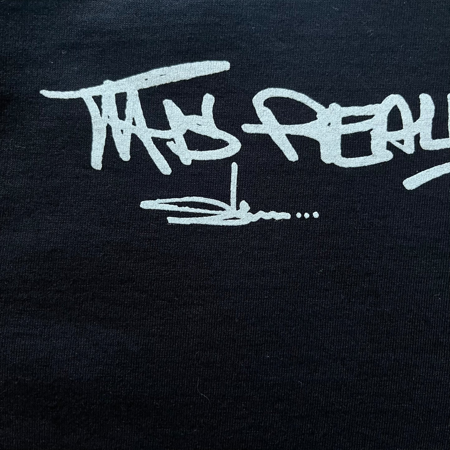 Black Batpreme tee designed by Slawn with Supreme Box Logo and his iconic Batman graphic on the front. Printed neck tag with signature and back shows handwritten-style text saying “This really isn’t real Supreme” with Slawn signature and the Supreme bogo. A rare, art-driven streetwear essential.