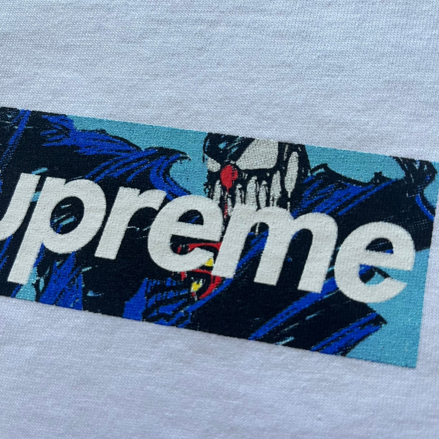 White Slawn Batpreme tee featuring a Batman-inspired graphic with iconic twist by Slawn and Supreme text overlay. Printed neck tag shows Slawn’s signature, while the back reads “This really isn’t real Supreme” in hand-drawn style with signature and logo. A striking, collectible streetwear piece.