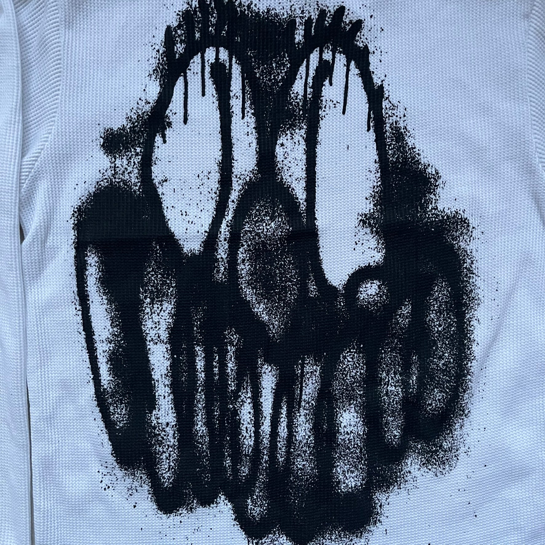 White waffle-knit / thermal long sleeve top made from textured fabric. Features a large black back print of Slawn’s dripping graffiti face, printed with fine line detail and layered ink effects. The front is finished with a small Slawn signature print near the hem, along with a neck tag bearing the artist’s signature.