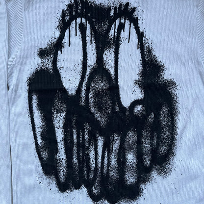 White waffle-knit / thermal long sleeve top made from textured fabric. Features a large black back print of Slawn’s dripping graffiti face, printed with fine line detail and layered ink effects. The front is finished with a small Slawn signature print near the hem, along with a neck tag bearing the artist’s signature.