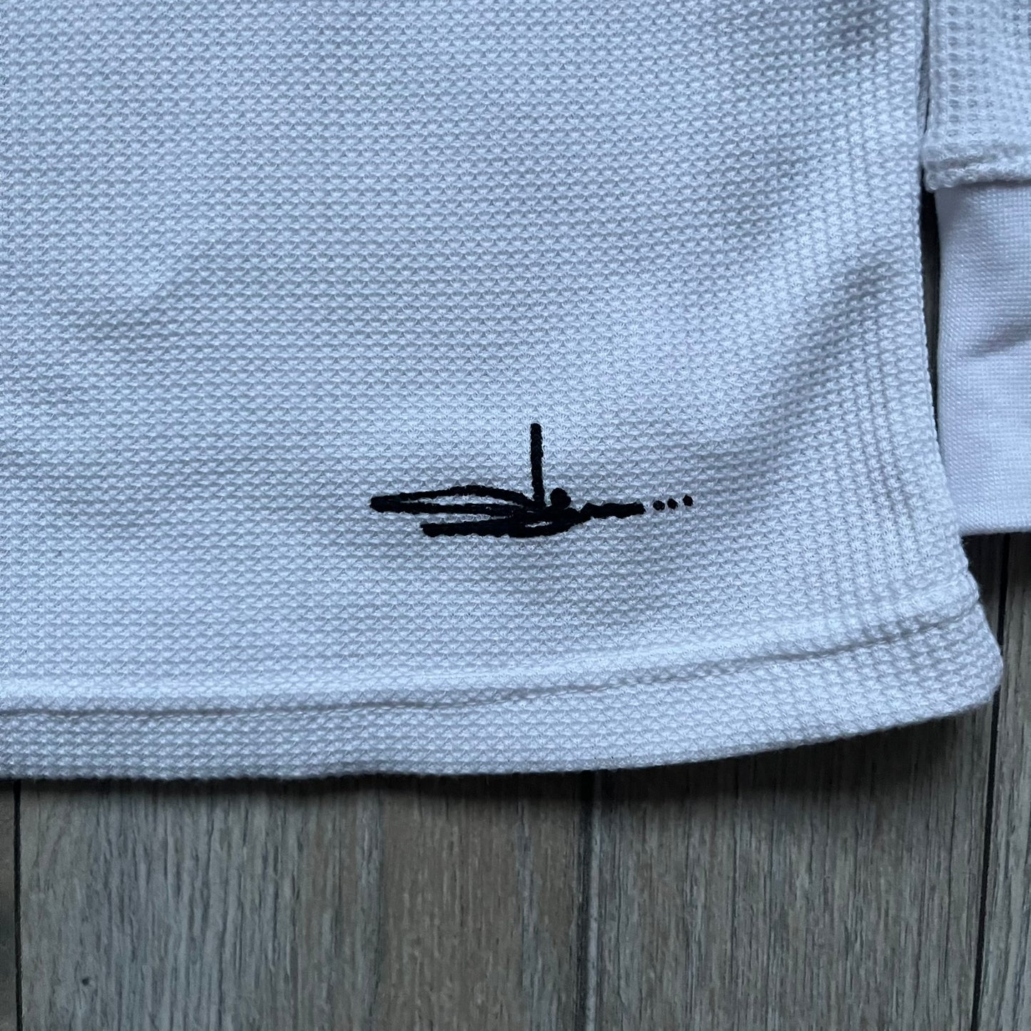 White waffle-knit / thermal long sleeve top made from textured fabric. Features a large black back print of Slawn’s dripping graffiti face, printed with fine line detail and layered ink effects. The front is finished with a small Slawn signature print near the hem, along with a neck tag bearing the artist’s signature.