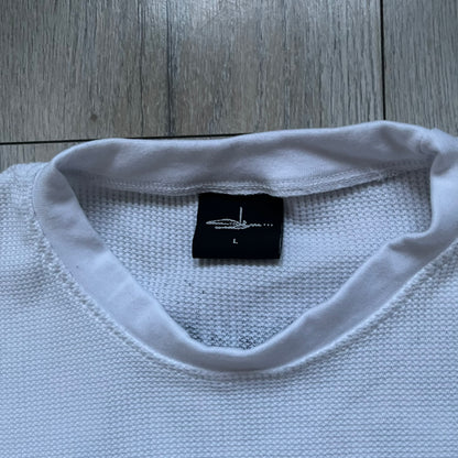White waffle-knit / thermal long sleeve top made from textured fabric. Features a large black back print of Slawn’s dripping graffiti face, printed with fine line detail and layered ink effects. The front is finished with a small Slawn signature print near the hem, along with a neck tag bearing the artist’s signature.