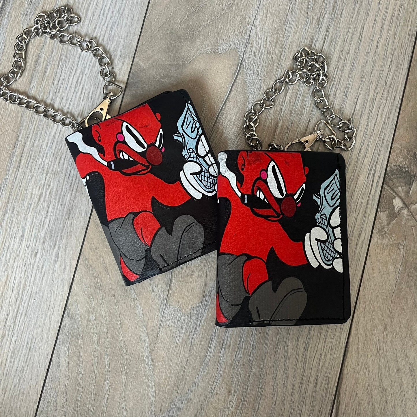 Slawn Leather Chain Man Wallet is a black foldable leather wallet featuring original artwork by Slawn on the front, depicting a red running figure holding a revolver and smoking a cigar. The wallet includes an attached metal chain for securing to clothing, along with eight card compartments and one top compartment for cash.