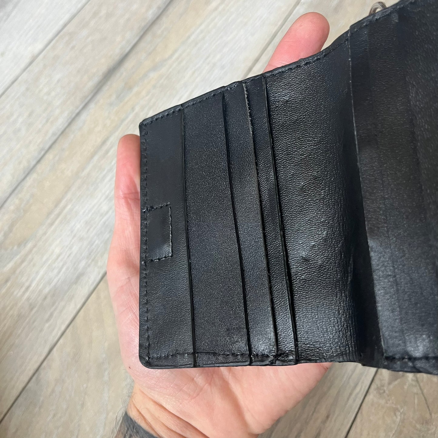 Slawn Leather Chain Man Wallet is a black foldable leather wallet featuring original artwork by Slawn on the front, depicting a red running figure holding a revolver and smoking a cigar. The wallet includes an attached metal chain for securing to clothing, along with eight card compartments and one top compartment for cash.