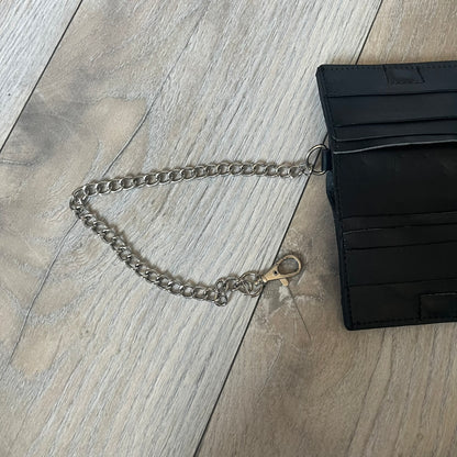 Slawn Leather Chain Man Wallet is a black foldable leather wallet featuring original artwork by Slawn on the front, depicting a red running figure holding a revolver and smoking a cigar. The wallet includes an attached metal chain for securing to clothing, along with eight card compartments and one top compartment for cash.