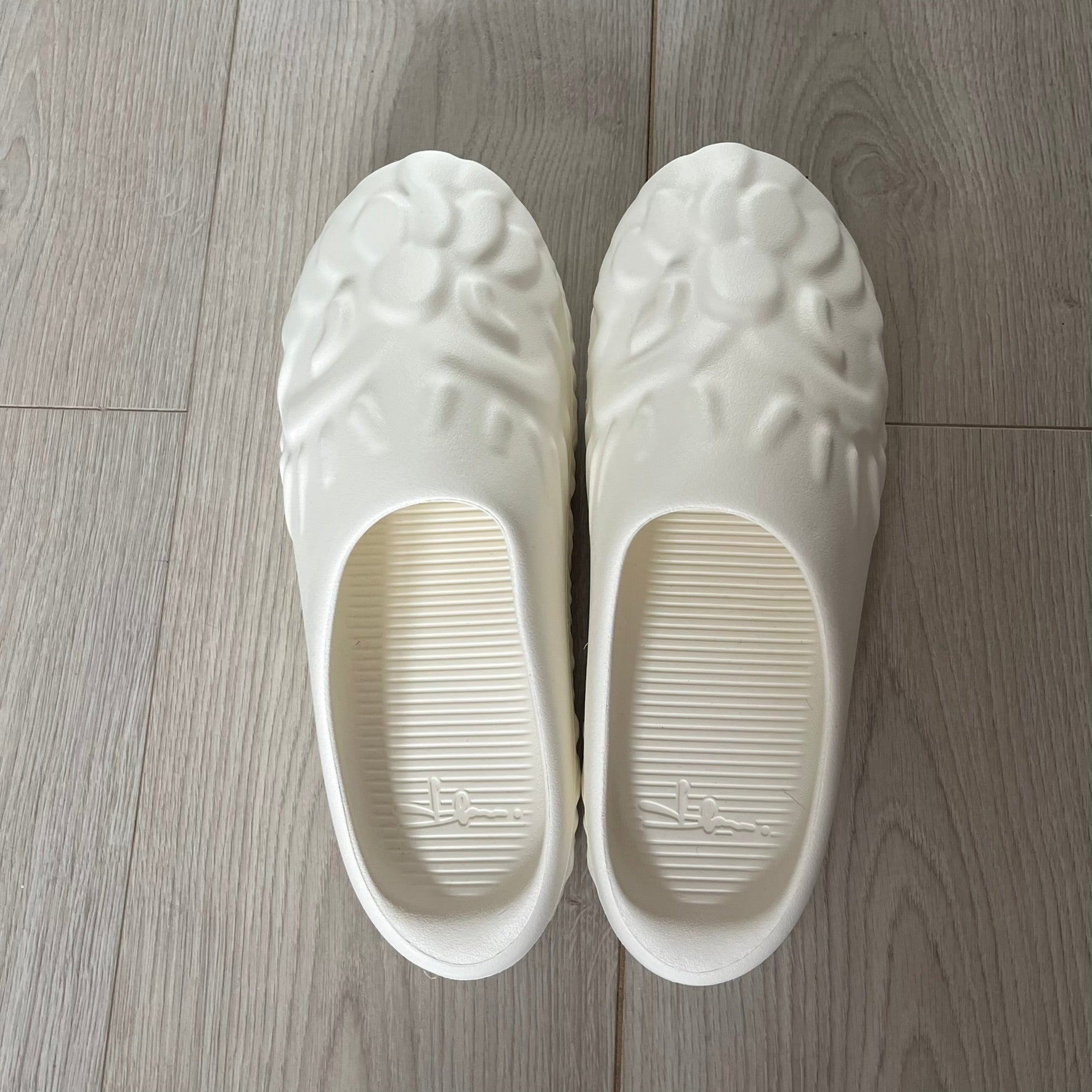 Slawn Shapes Snow Stompaz Sliders in the white colorway, created in collaboration with artist Olaolu Slawn and Shape Shoes. These closed-toe rubber sliders feature Slawn’s signature cartoonish face design forming the body of the shoe and the playful tagline “F*ck Crusty Toes.” The tread is specially designed to leave a unique footprint. They come packaged in a cardboard box filled with snow-like wool and include a special silver sticker.