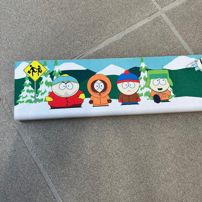 South Park 1998 Keyboard Wrist Rest is a thick foam wrist rest featuring the iconic bus stop scene with Cartman, Kenny, Stan, and Kyle kicking Ike. The design includes the wooden South Park sign and a small 1998 Comedy Central licensing mark, with a black base.