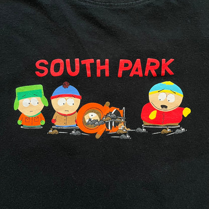 South Park 2000 Kenny’s Rats Black Tee is a black short-sleeve T-shirt with a Comedy Central 2000 licensed neck tag. The front features red “South Park” text above a graphic of Kenny, Stan, and Cartman standing while Kenny is depicted on the ground being eaten by rats. The shirt has a simple boxy fit with a front print design.