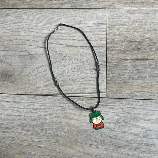 South Park 2000 Kyle Necklace features a black cord necklace with a metal pendant shaped as Kyle from South Park. The back of the pendant is marked with 2000 Comedy Central and Sedesma licensing details.