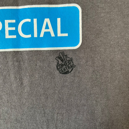 South Park 2008 Timmy “I’m Special” Tee features a grey T-shirt with a front graphic of Timmy’s face above a blue bar with white “I’m Special” text. Small 2008 licensing and Comedy Central details are printed underneath. The back features a blue and white wheelchair-accessibility sign graphic. Includes a licensed South Park neck tag.

