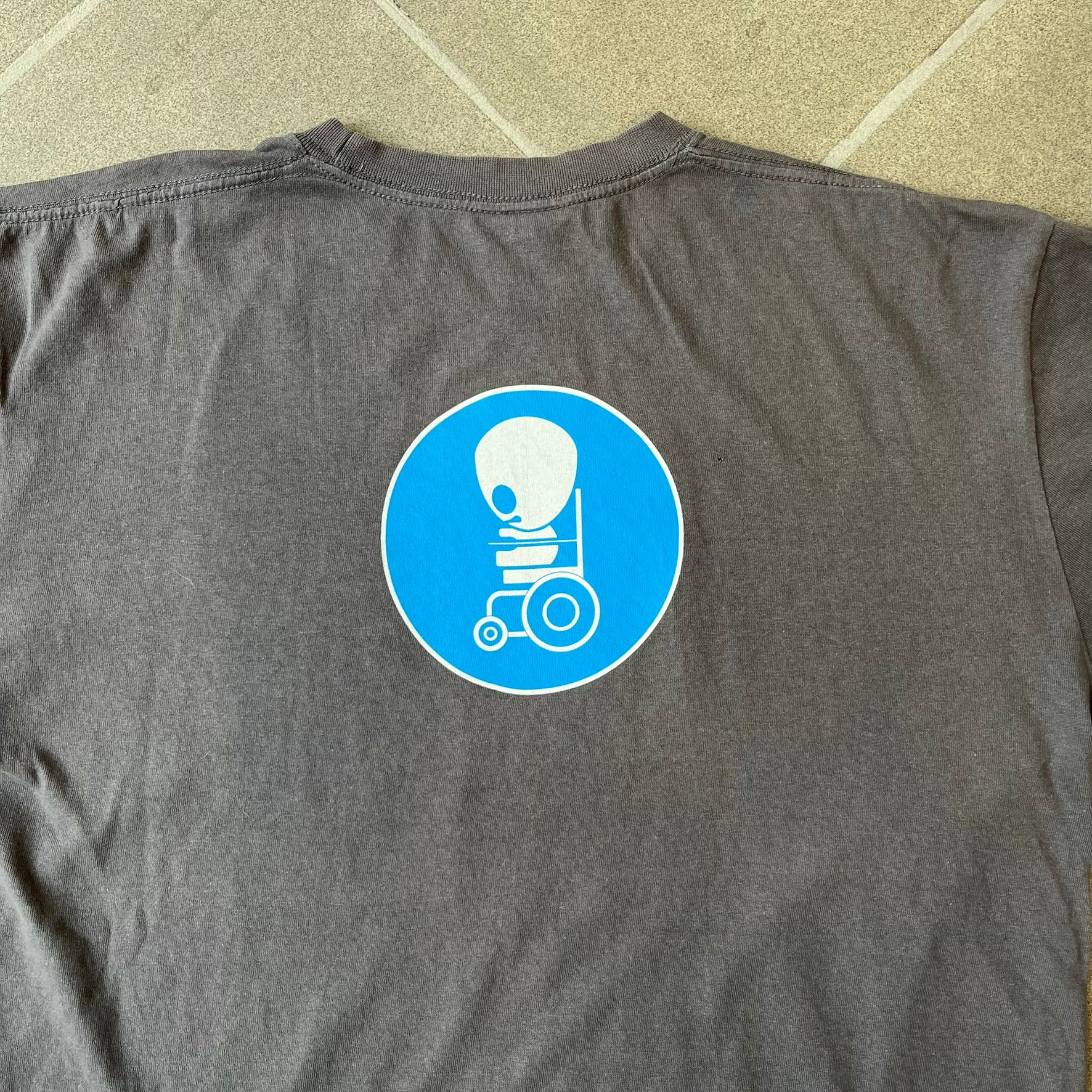 South Park 2008 Timmy “I’m Special” Tee features a grey T-shirt with a front graphic of Timmy’s face above a blue bar with white “I’m Special” text. Small 2008 licensing and Comedy Central details are printed underneath. The back features a blue and white wheelchair-accessibility sign graphic. Includes a licensed South Park neck tag.
