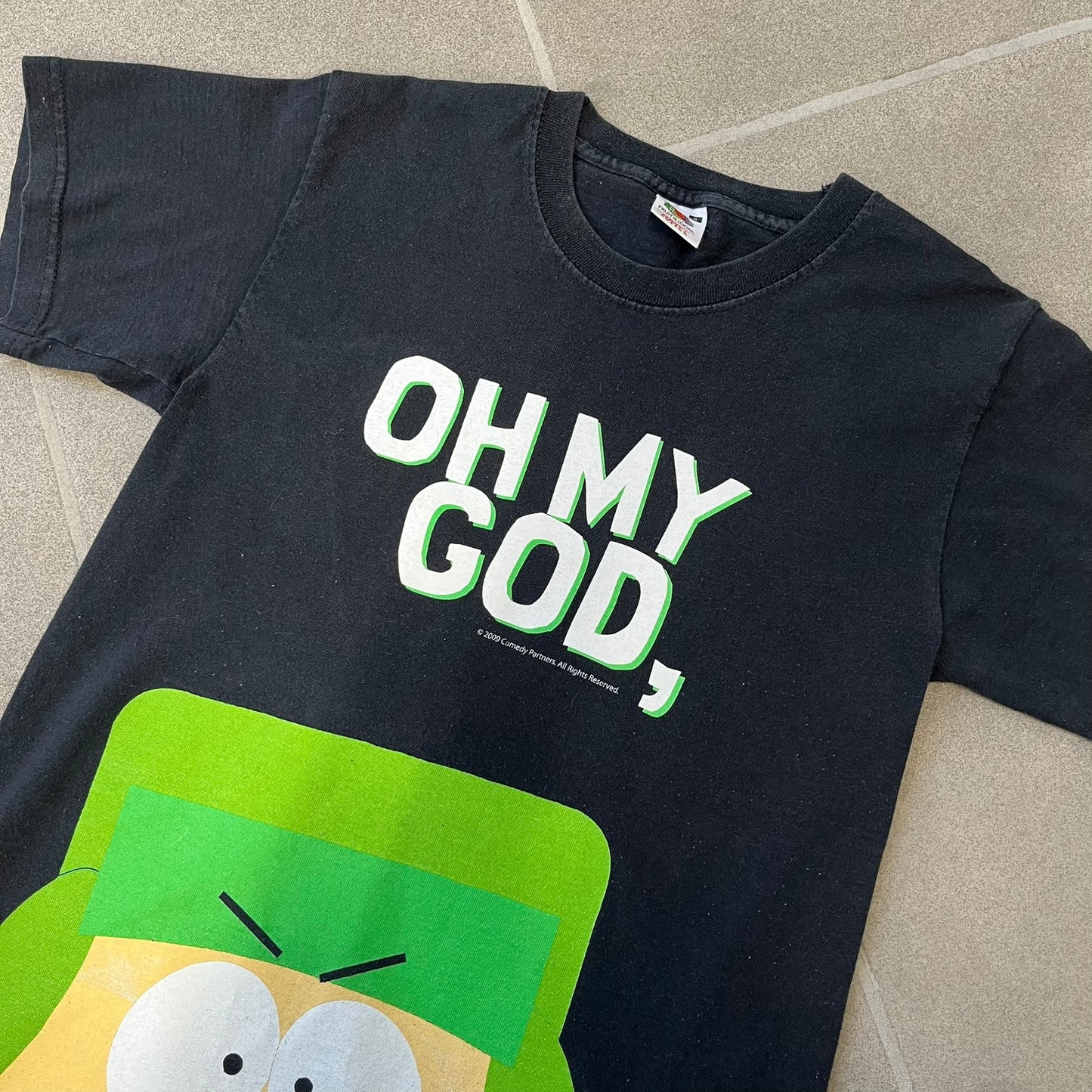 South Park 2009 “Oh My God, They Killed Kenny!” Tee is a black T-shirt made on a Fruit of the Loom blank. The front features a large graphic of Kyle with “Oh My God,” printed above and 2009 South Park licensing below. The back shows a stitched version of Kenny with “They Killed Kenny!” printed above the graphic.
