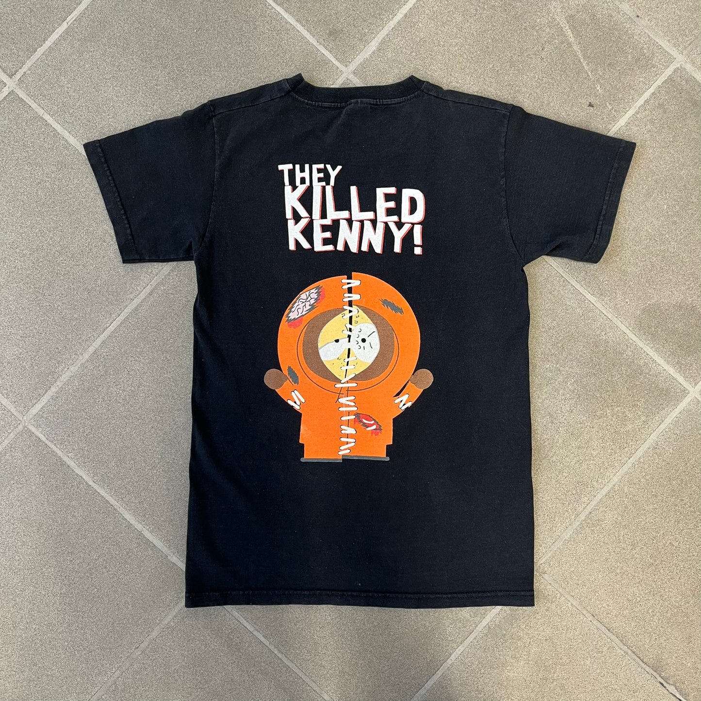 South Park 2009 “Oh My God, They Killed Kenny!” Tee is a black T-shirt made on a Fruit of the Loom blank. The front features a large graphic of Kyle with “Oh My God,” printed above and 2009 South Park licensing below. The back shows a stitched version of Kenny with “They Killed Kenny!” printed above the graphic.
