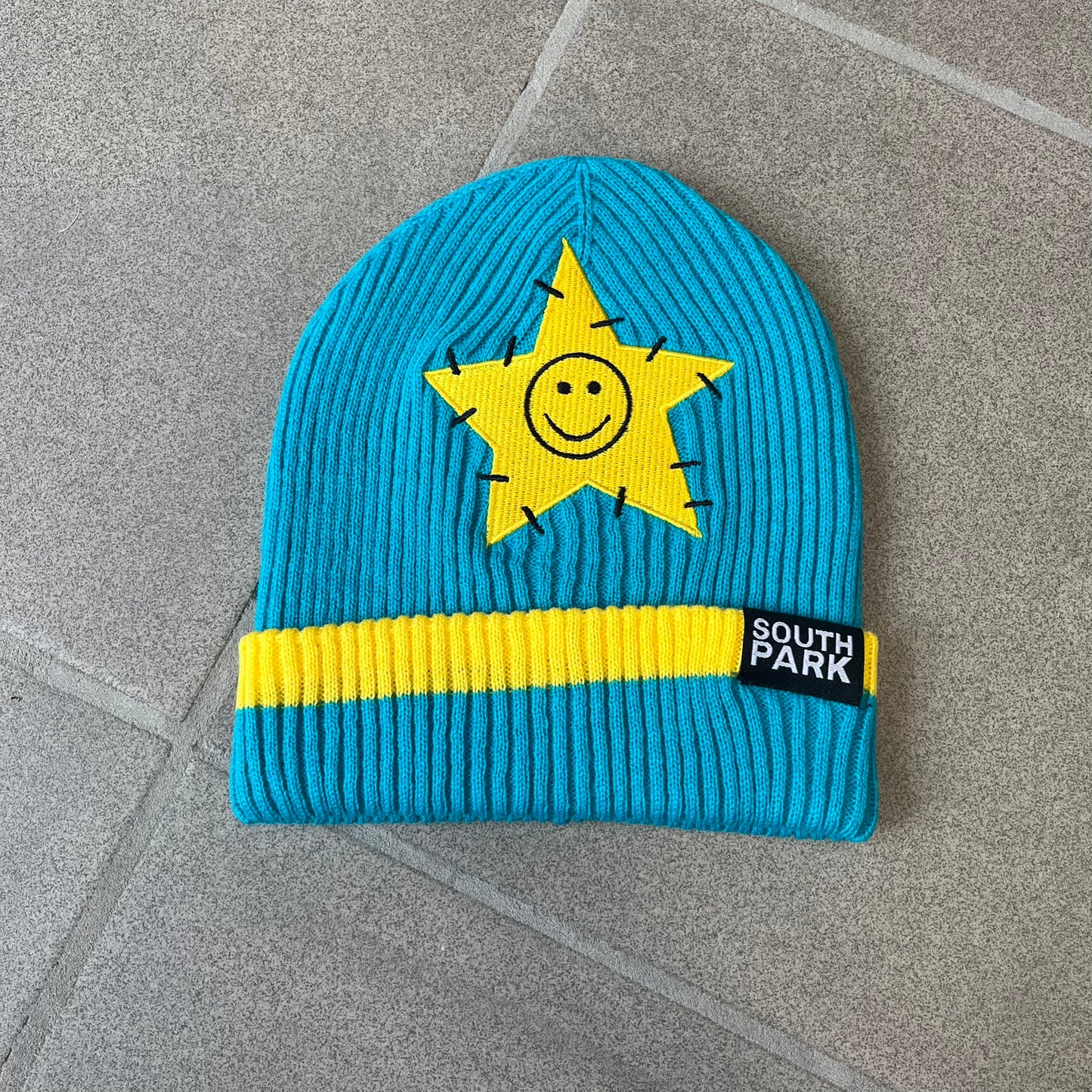 Exclusive South Park Snow Day Collector’s Edition Grand Wizard Cartman Beanie. Teal knit with yellow stripe detailing, embroidered yellow star with stitched effect, and official South Park branding tag. Made from a soft, stretchy material for a comfortable fit.