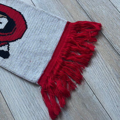 Vintage football scarf in white and black with red fringe / tassels, featuring South Park characters including Kenny, Cartman, and Kyle dressed in Arsenal kits with “Gooners” text. The character graphics appear on both sides of the scarf, with consistent coloring in white and red. Soft knit construction with a classic football scarf shape and finish.