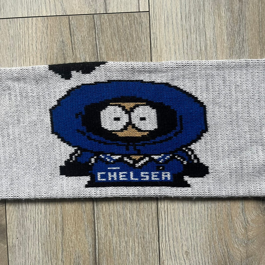 Vintage football scarf in white and black with blue fringe / tassels, featuring South Park characters including Kenny, Cartman, and Kyle dressed in Chelsea kits. The character graphics appear on both sides of the scarf, with consistent coloring in blue. Soft knit construction with a classic football scarf shape and finish.