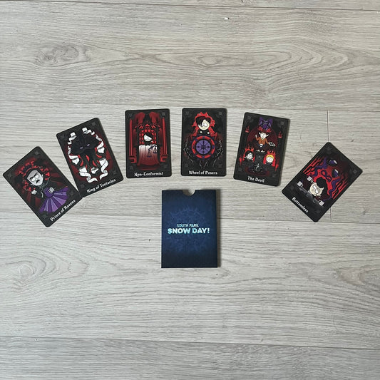 Set of 6 South Park Snow Day tarot cards, exclusive to the Collector’s Edition. Features characters like the Emo Kids with designs such as “Prince of Ravens” and “Non-Conformist.” Each card has dark red and black front artwork with a blue South Park Snow Day back.