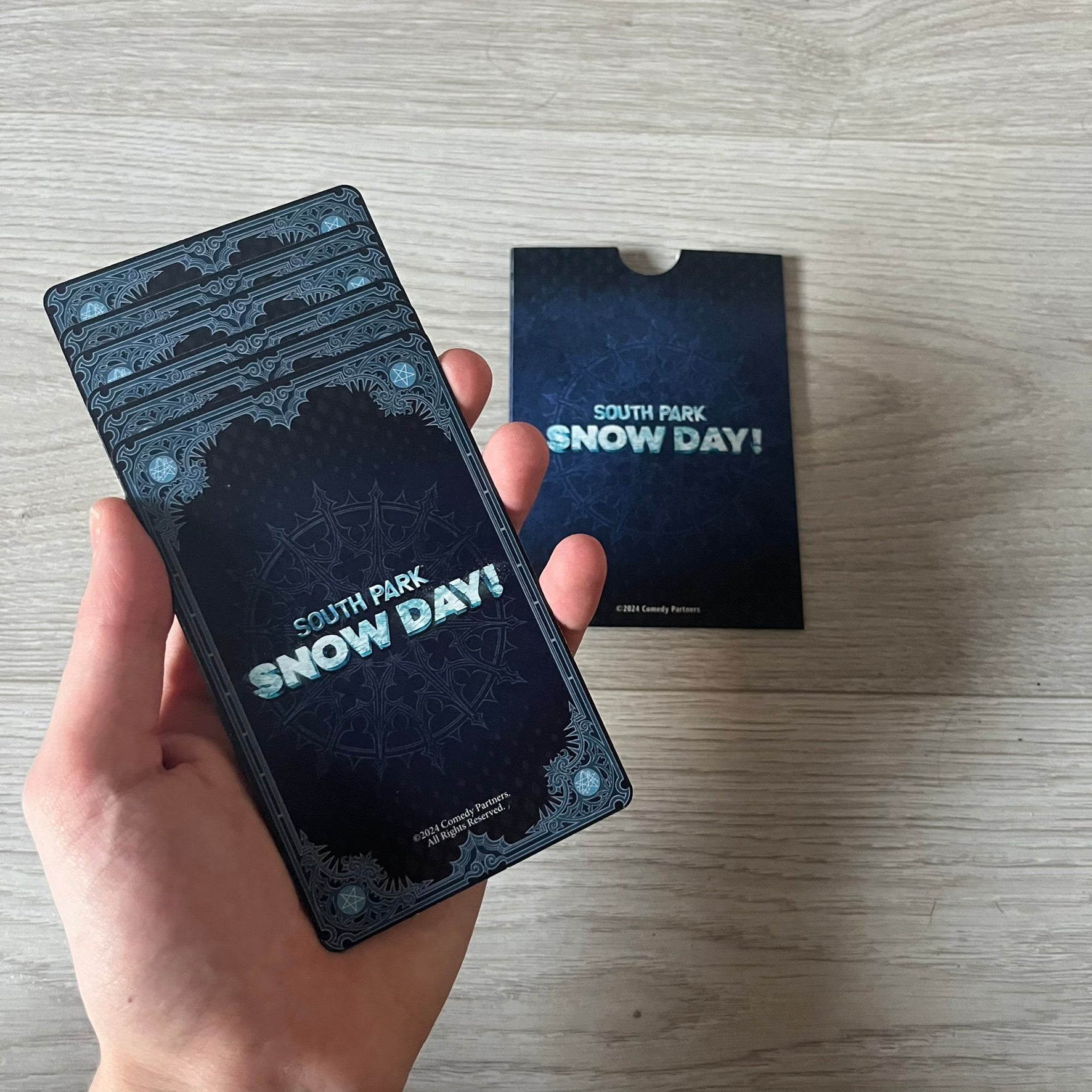 Set of 6 South Park Snow Day tarot cards, exclusive to the Collector’s Edition. Features characters like the Emo Kids with designs such as “Prince of Ravens” and “Non-Conformist.” Each card has dark red and black front artwork with a blue South Park Snow Day back.