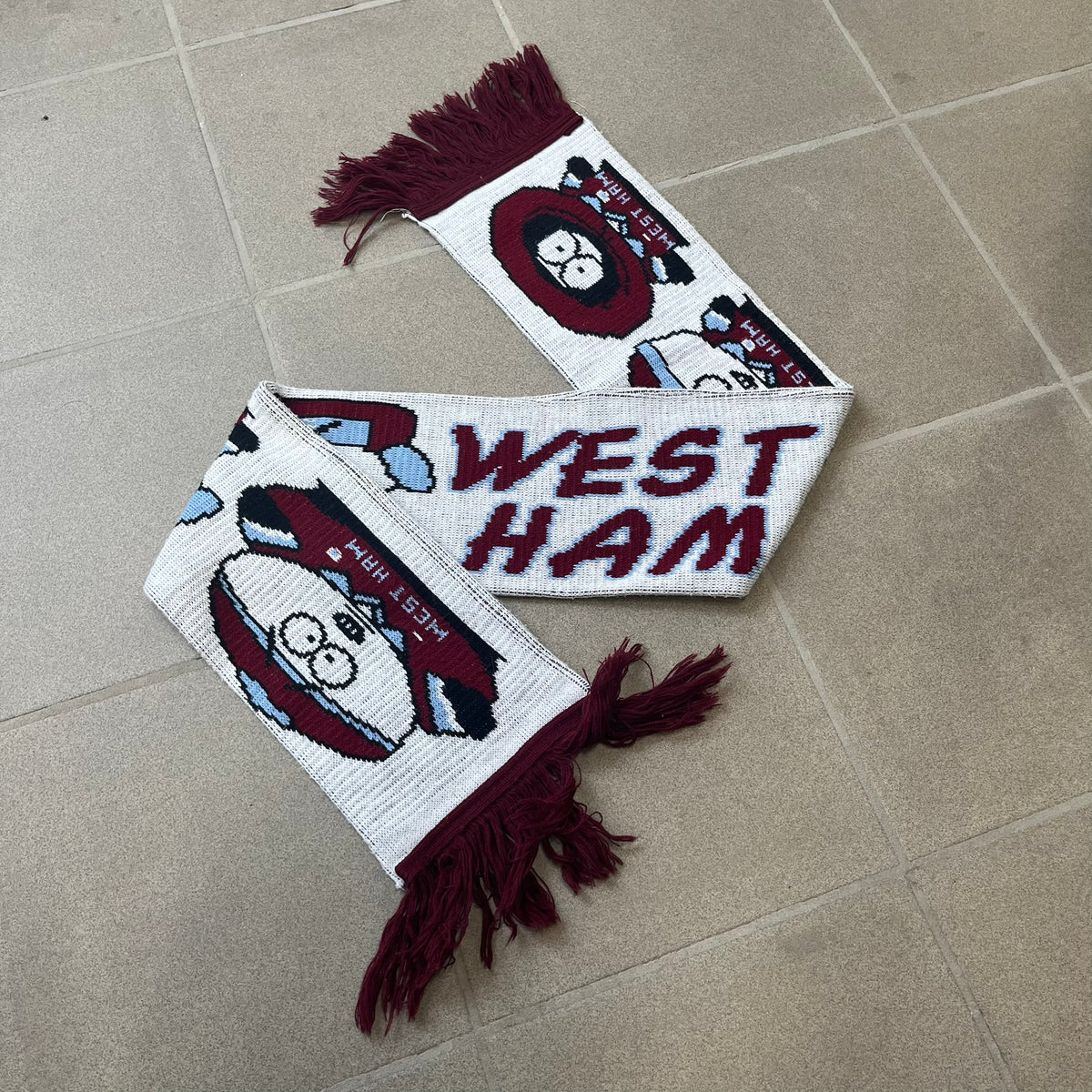 Vintage South Park West Ham 1990's Football Scarf in white and burgundy with fringe / tassels, featuring South Park characters including Kenny, Cartman, Kyle and Stan dressed in West Ham kits. The character graphics appear on both sides of the scarf, with consistent coloring in Burgundy and light blue.