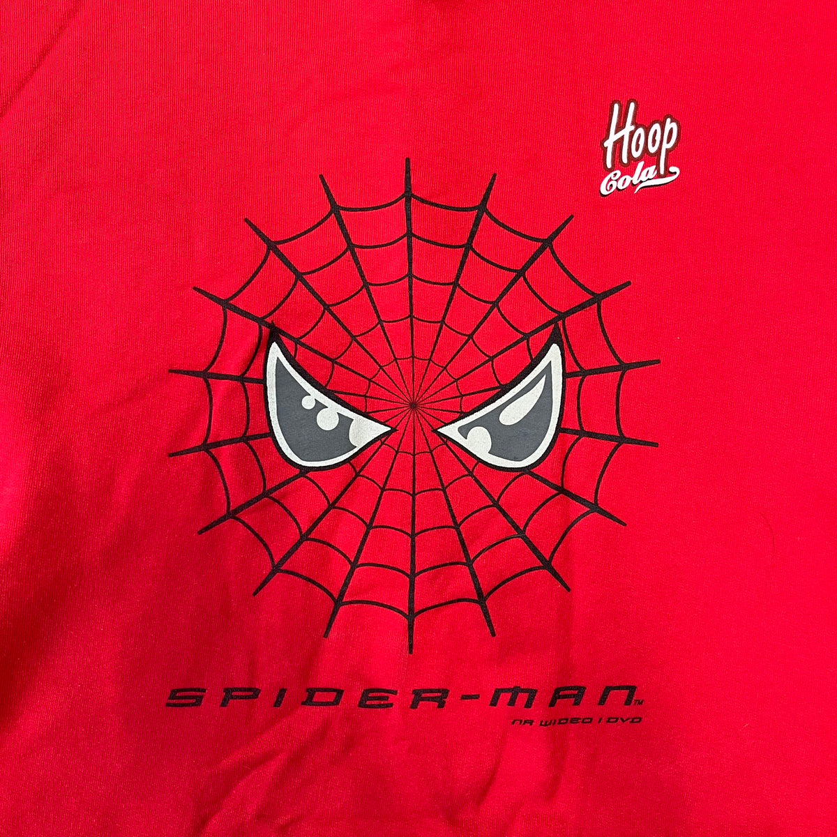 Spider-Man 2002 Hoop Cola Promo Red Crewneck is a rare Poland-exclusive crewneck made for the cross-promotional campaign between Hoop Cola and Warner Bros for the Spider-Man (2002) film. It was never sold in stores and was given out only as a prize in the SMS code contest. The cotton crewneck features web with eyes graphic in the middle, Spider-Man logo under and a Hoop Cola logo above.