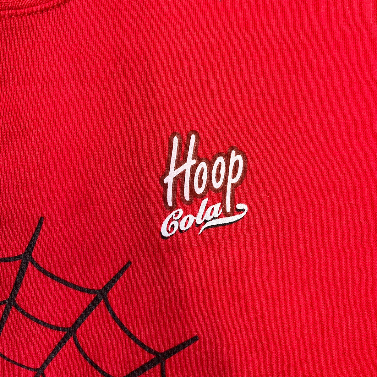 Spider-Man 2002 Hoop Cola Promo Red Crewneck is a rare Poland-exclusive crewneck made for the cross-promotional campaign between Hoop Cola and Warner Bros for the Spider-Man (2002) film. It was never sold in stores and was given out only as a prize in the SMS code contest. The cotton crewneck features web with eyes graphic in the middle, Spider-Man logo under and a Hoop Cola logo above.
