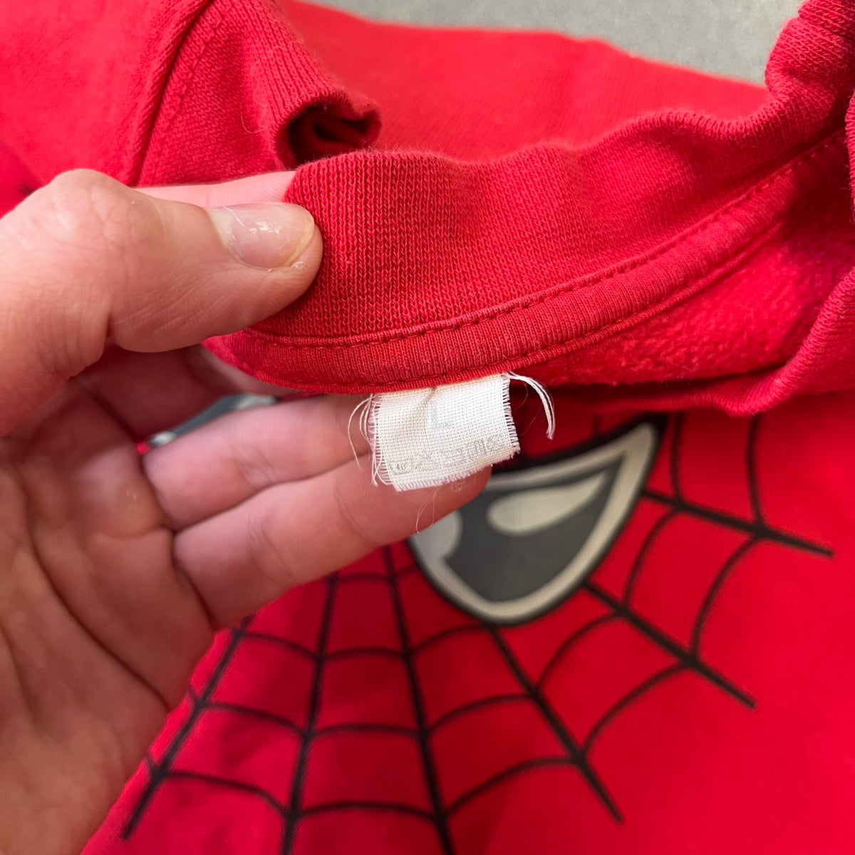Spider-Man 2002 Hoop Cola Promo Red Crewneck is a rare Poland-exclusive crewneck made for the cross-promotional campaign between Hoop Cola and Warner Bros for the Spider-Man (2002) film. It was never sold in stores and was given out only as a prize in the SMS code contest. The cotton crewneck features web with eyes graphic in the middle, Spider-Man logo under and a Hoop Cola logo above.