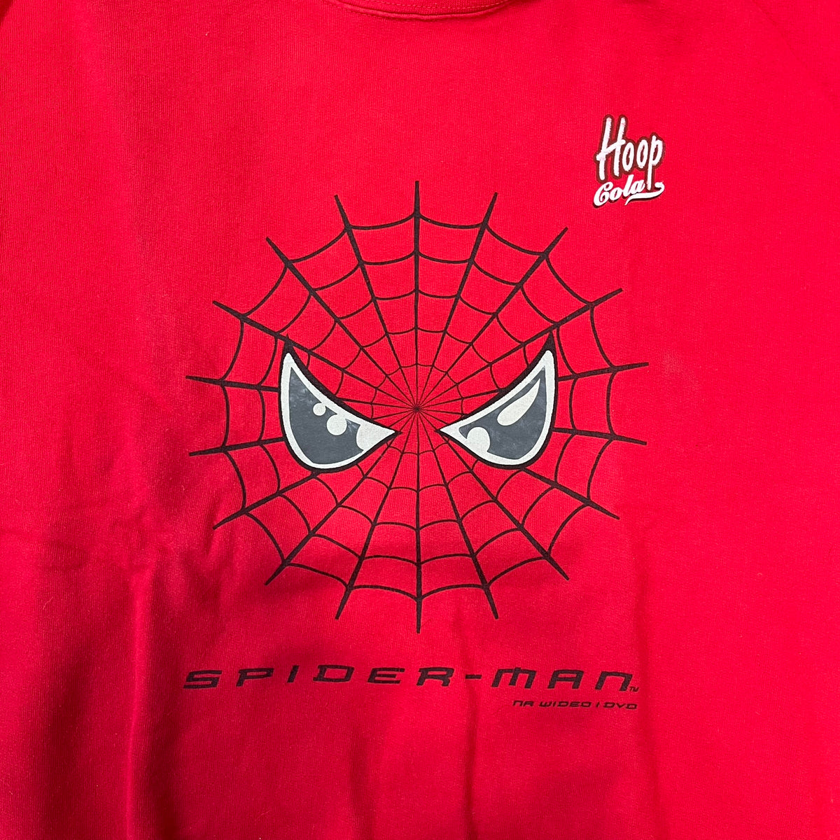Spider-Man 2002 Hoop Cola Promo Red Crewneck is a rare Poland-exclusive crewneck made for the cross-promotional campaign between Hoop Cola and Warner Bros for the Spider-Man (2002) film. It was never sold in stores and was given out only as a prize in the SMS code contest. The cotton crewneck features web with eyes graphic in the middle, Spider-Man logo under and a Hoop Cola logo above.