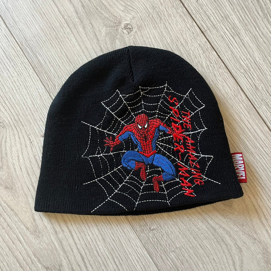 Black beanie with Spider-Man design on a wooden surface